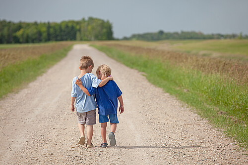 Two Caucasian Boys Walking Down a Country Road