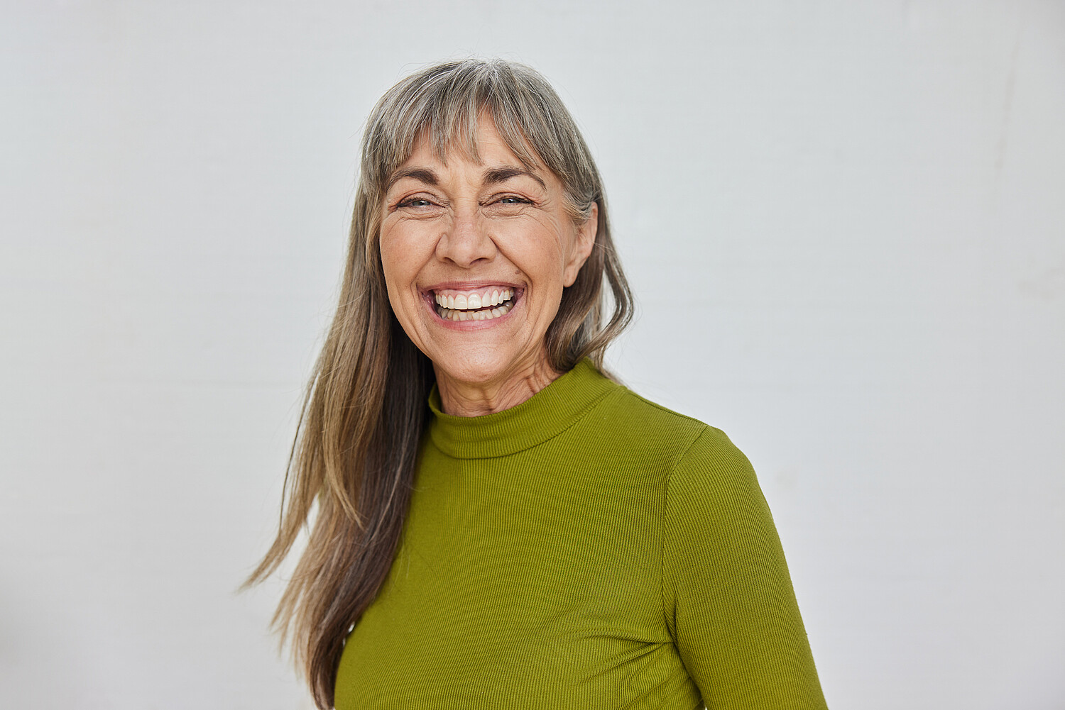 Carefree mature woman laughing against a gray background